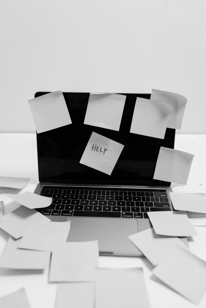 Services Black and white photo of a laptop covered with sticky notes, one labeled 'HELP'.